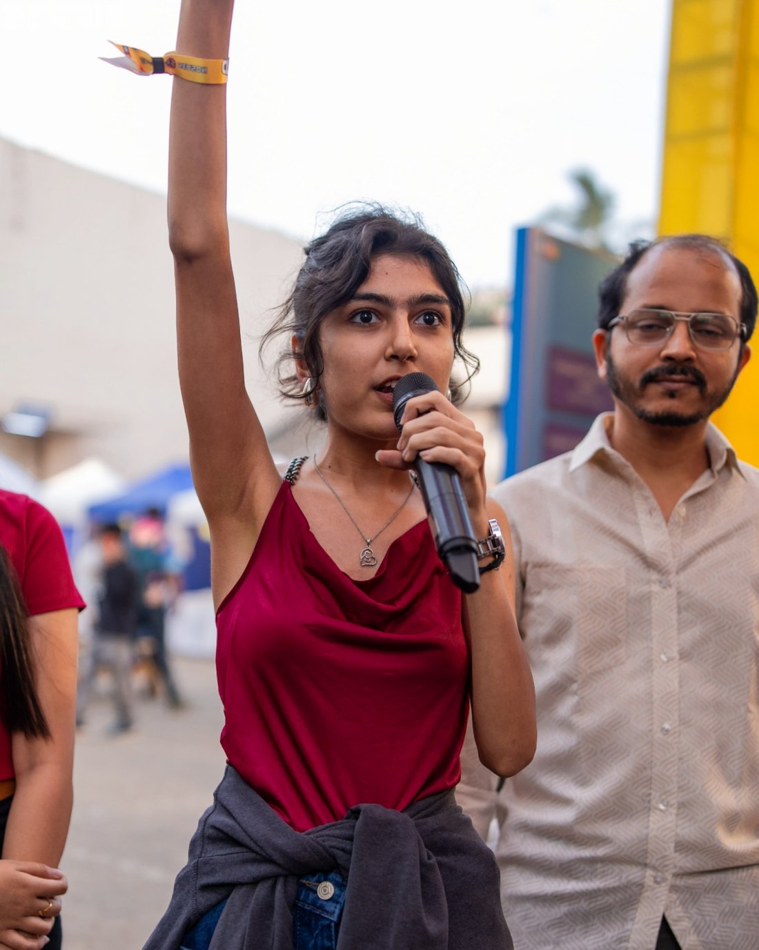 Diya Nathwani speaking into a microphone, arm raised